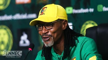 Homme en lunettes et casquette jaune lors d'une conférence de presse.