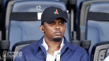 Samuel Eto’o assis dans les tribunes, expression sérieuse.