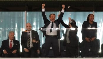 Homme en costume célébrant une victoire avec ses collègues.