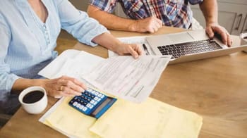 Deux personnes calculant leur pension de retraite avec documents et ordinateur.