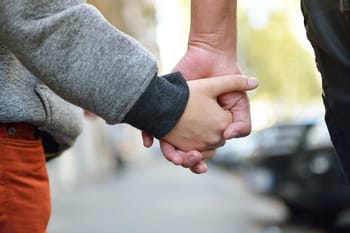 Main d'un adulte tenant la main d'un enfant dans la rue.