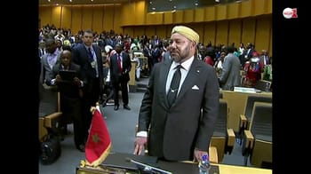 Homme en costume avec turban dans une salle de conférence pleine de personnes.