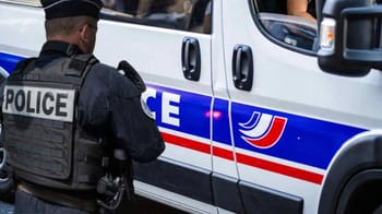 Policier en uniforme près d'un véhicule de police en France.