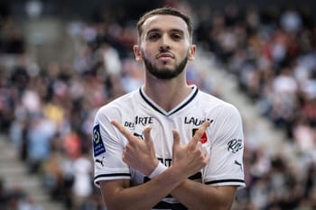 Amine Gouiri, joueur de football, en tenue blanche lors d'un match.