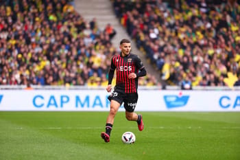 Jeune joueur de football en action lors d'un match avec un public nombreux.
