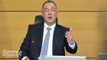 Lekjaa en costume parlant lors d'une conférence officielle.