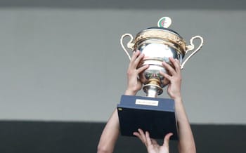 Personne levant un trophée de football en célébration.