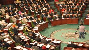 Débat parlementaire en Tunisie avec des députés assis en cercle.