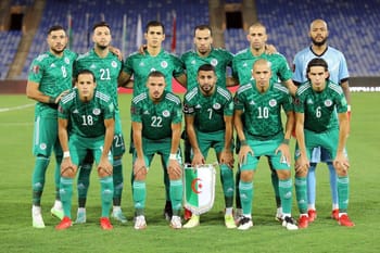 Groupe de joueurs de football algériens en uniforme vert sur le terrain.