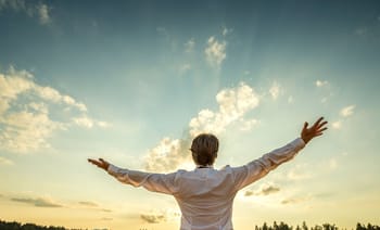 Homme avec bras ouverts regardant le ciel en plein jour.