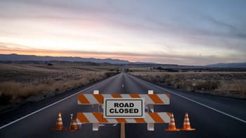 Route fermée avec barrière et panneau 'Road Closed' en plein désert.