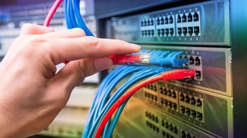 Technicien connectant des câbles réseau en fibre optique dans un centre de données.