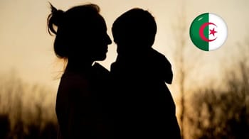 Silhouette d'une mère algérienne tenant son fils dans un décor en sunset.