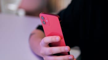 Enfant tenant un iPhone 11 rouge dans la main.