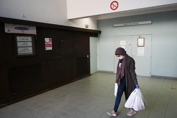 Femme portant un masque et des gants dans un hall d'hôpital en France.