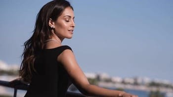 Hiba Abouk en tenue noire, regardant vers la droite avec un fond marin.
