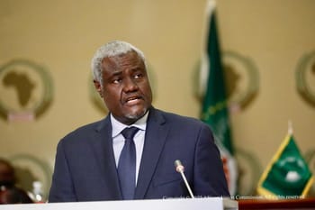 Homme africain en costume parlant lors d'une réunion officielle.