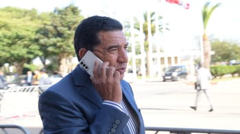 Homme en costume parlant au téléphone dans un espace extérieur.