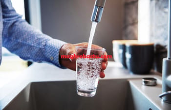 Eau potable en train d'être filtrée dans un verre sous un robinet.
