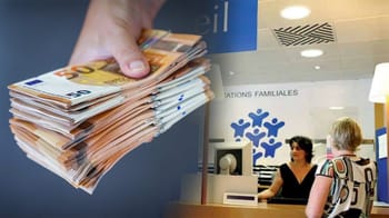 Main tenant une pile de billets de 50 euros dans un bureau administratif.