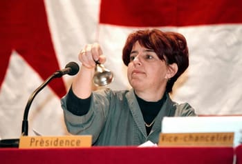 Elisabeth Baume-Schneider agitant une cloche lors d'une réunion officielle.
