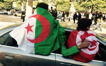 Deux supporters algériens avec drapeaux lors d'un événement public.