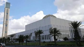 Vue extérieure de la grande mosquée d'Alger avec palmiers et ciel nuageux.