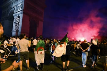 Manifestation à Paris avec drapeaux algériens et ciel coloré au coucher du soleil.