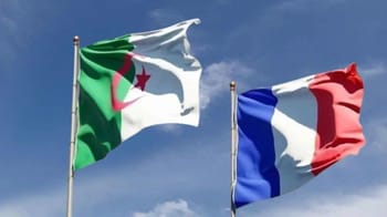 Drapeaux d'Algérie et de France flottant dans le ciel bleu.