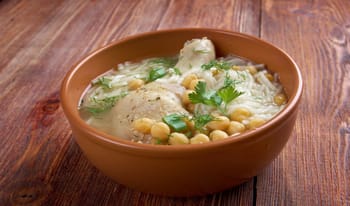 Soupe Chorba Beida dans un bol en terre cuite avec herbes et pois chiches.