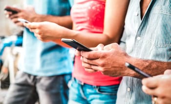 Groupe de personnes utilisant des smartphones en extérieur.