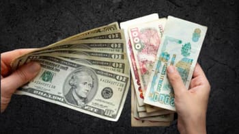 Main tenant des billets de dollars et de dinars algériens.