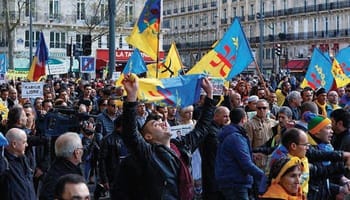 Manifestation en France avec drapeaux kabyles et pancartes.