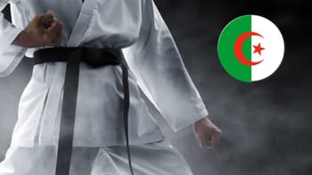 Pratiquant de karaté en uniforme avec drapeau algérien en arrière-plan.