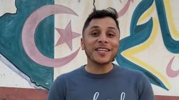 Jeune homme souriant devant un graffiti coloré en Algérie.