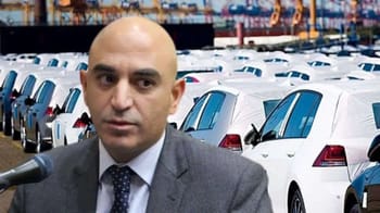 Expert automobile parlant devant une grande flotte de voitures.