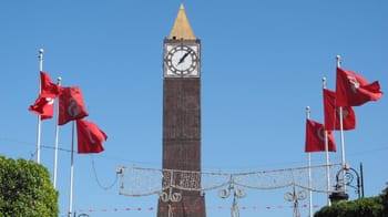 Horloge de Tunis avec drapeaux tunisiens en arrière-plan.