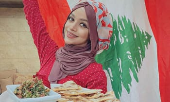 Jeune femme libanaise avec hijab, souriante, devant drapeau libanais.