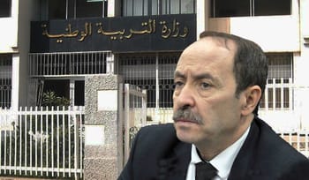Homme en costume devant le bâtiment du ministère de l’Éducation nationale.