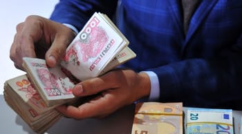 Hommes tenant des billets de dinar algérien en main.