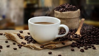 Tasse de café chaud avec grains de café en arrière-plan.