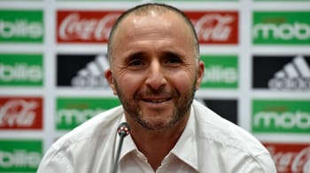 Djamel Belmadi souriant lors d'une conférence de presse sportive.