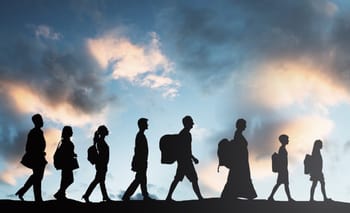 Groupe de migrants marchant sous un ciel nuageux au coucher du soleil.