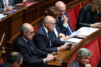 Députés en séance parlementaire, concentrés sur leurs appareils et documents.