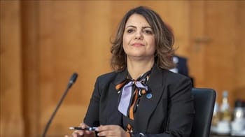 Femme politique libyenne en réunion, portant un costume noir et un foulard coloré.