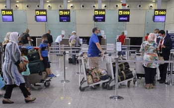 Passagers à l'aéroport d'Alger avec valises et comptoirs d'enregistrement.