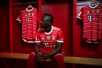 Joueur du Bayern Munich dans le vestiaire avec maillot rouge.