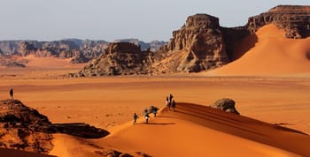 Vue du désert du Sahara algérien avec dunes et formations rocheuses.