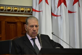 Salah Goudjil en costume lors d'une réunion officielle avec drapeaux en arrière-plan.