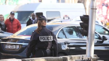 Policière en action près d'une voiture noire en ville.